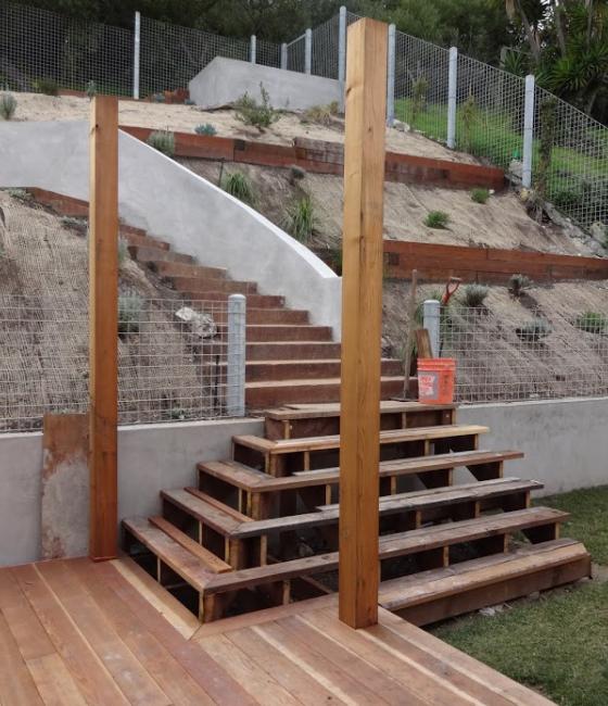 and under construction backyard with netting on the plants and a new wooden staircase